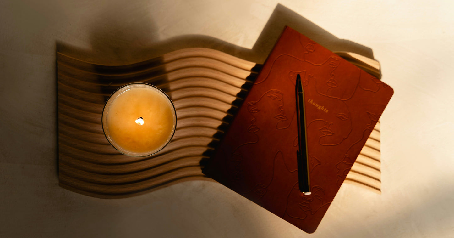 A lit candle and closed journal resting on a wooden surface in warm light — for an essay on the difference between wishes and genuine intention.