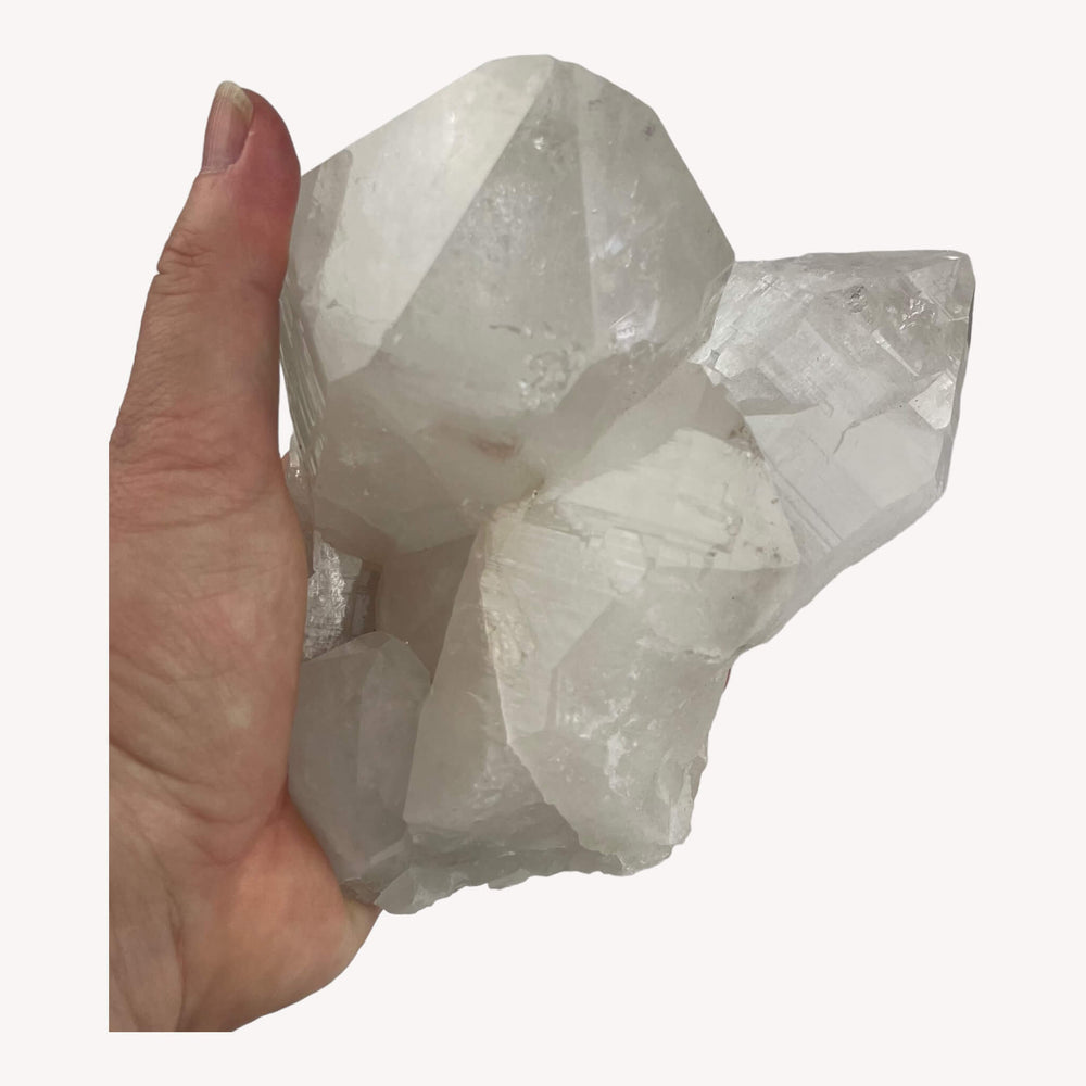 Clear Quartz crystal cluster held in hand, revealing its size and captivating details. The crystal's transparency and radiant energy make it a powerful addition to any crystal enthusiast's collection.