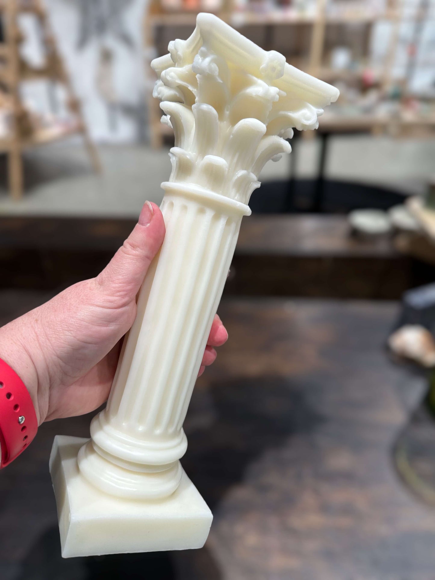 Hand holding the Corinthian Pillar Candle by With Love Ally, showcasing its dimensions (30cm L x 9cm W x 9cm H). Crafted from a sustainable beeswax blend, this unscented candle is a statement piece, adding elegance and style to any space
