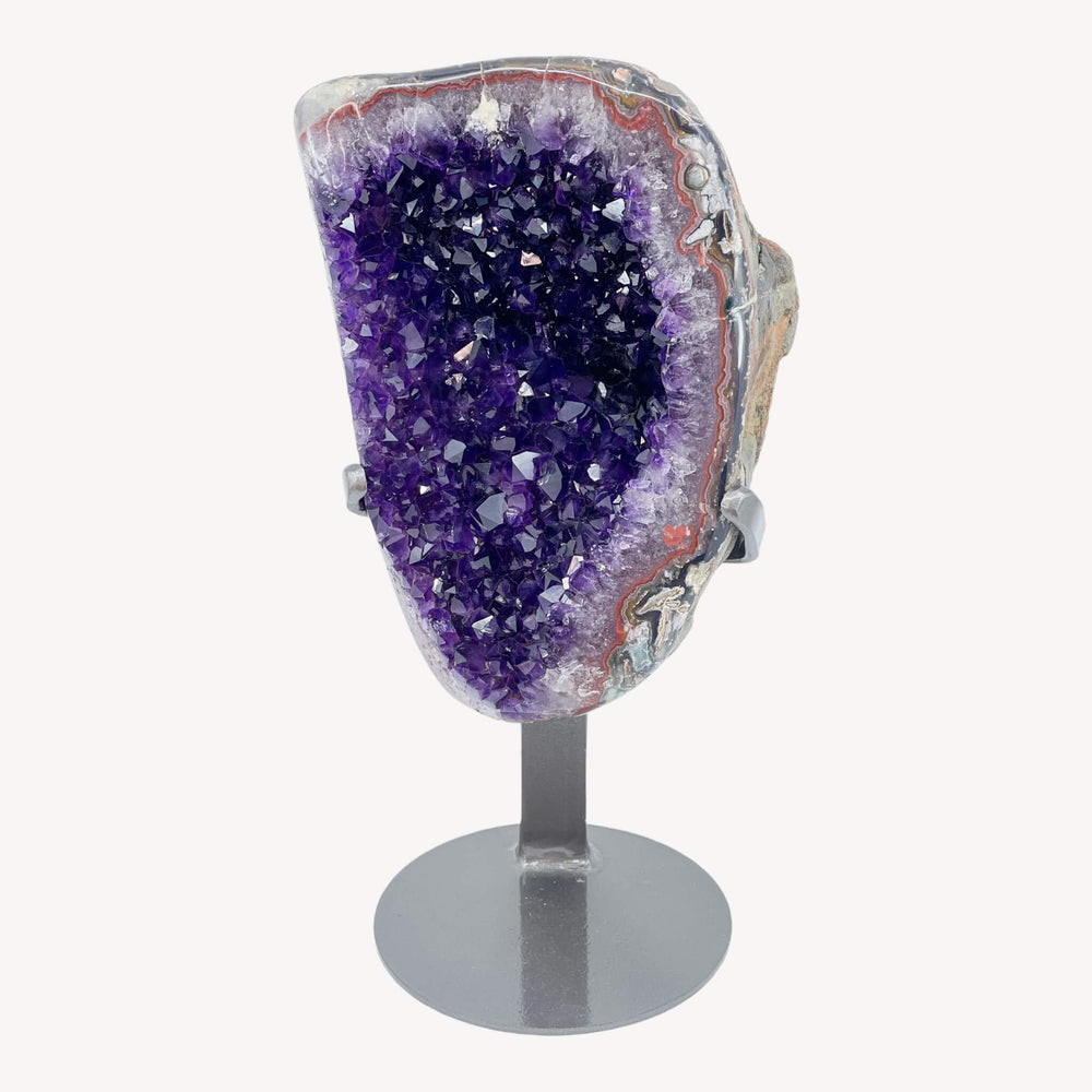 A Grade Amethyst Crystal Cluster from Uruguay weighing 3.3kg, elegantly displayed on a stand. Rich purple hues and intricate crystal formations create a mesmerising centrepiece for positive energy.