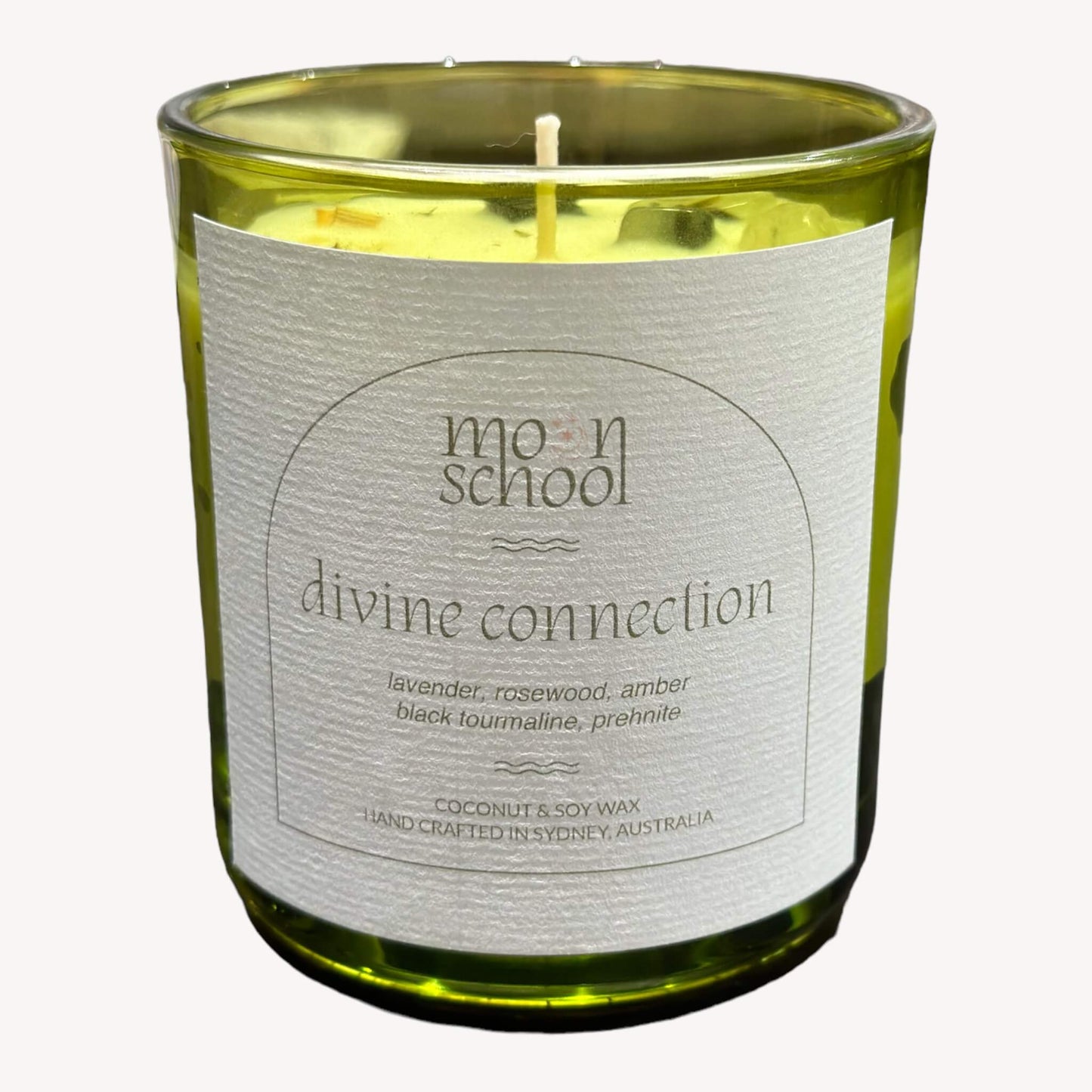 Front view of Moon School's DIVINE CONNECTION Crystal Candle in the small size (200mls). Housed in a charming retro green glass jar, this candle combines the serene scents of lavender, rosewood, and amber, creating a tranquil atmosphere.