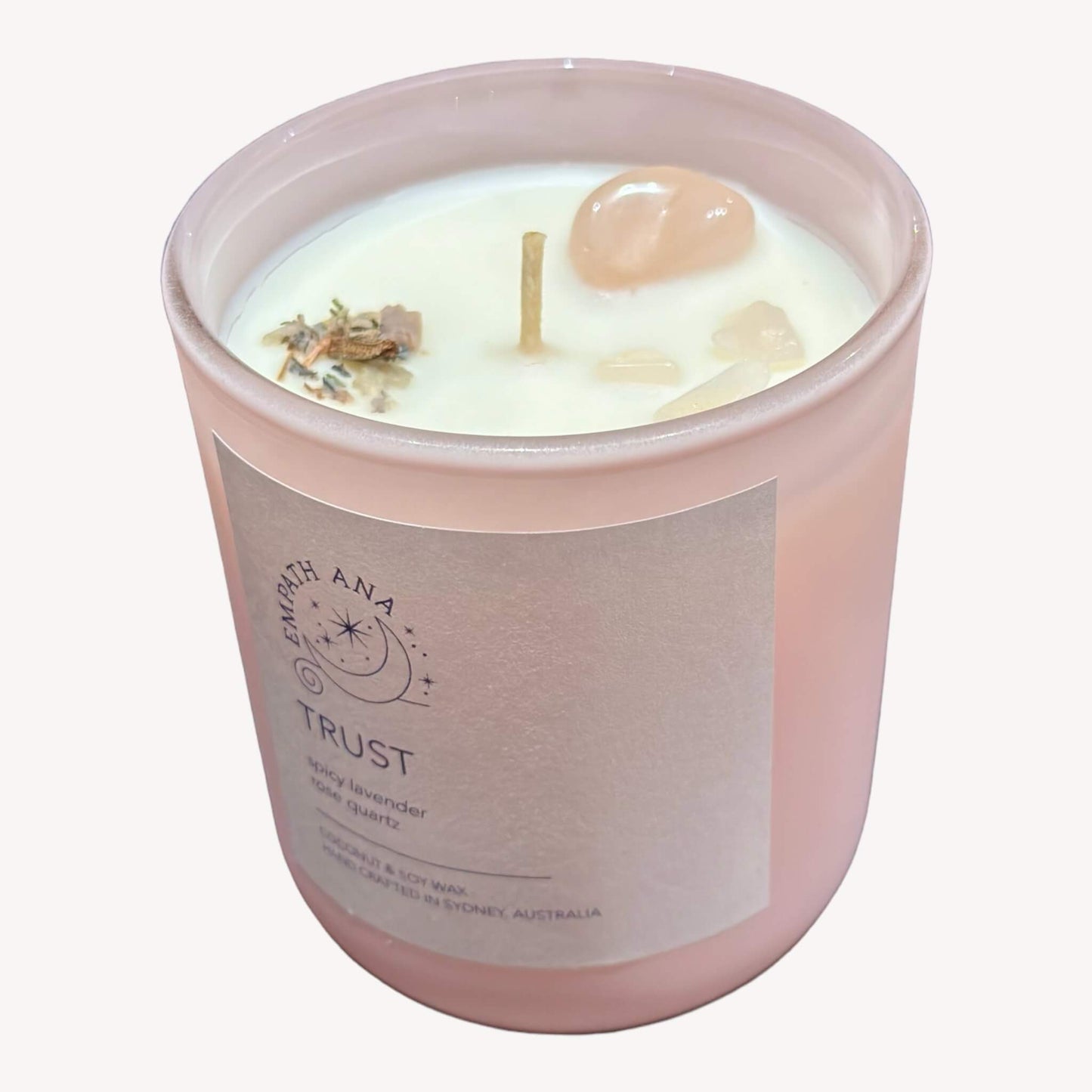 Top view of the medium Trust Crystal Candle showing off the Rose Quartz crystal decor, cotton wick and herbs