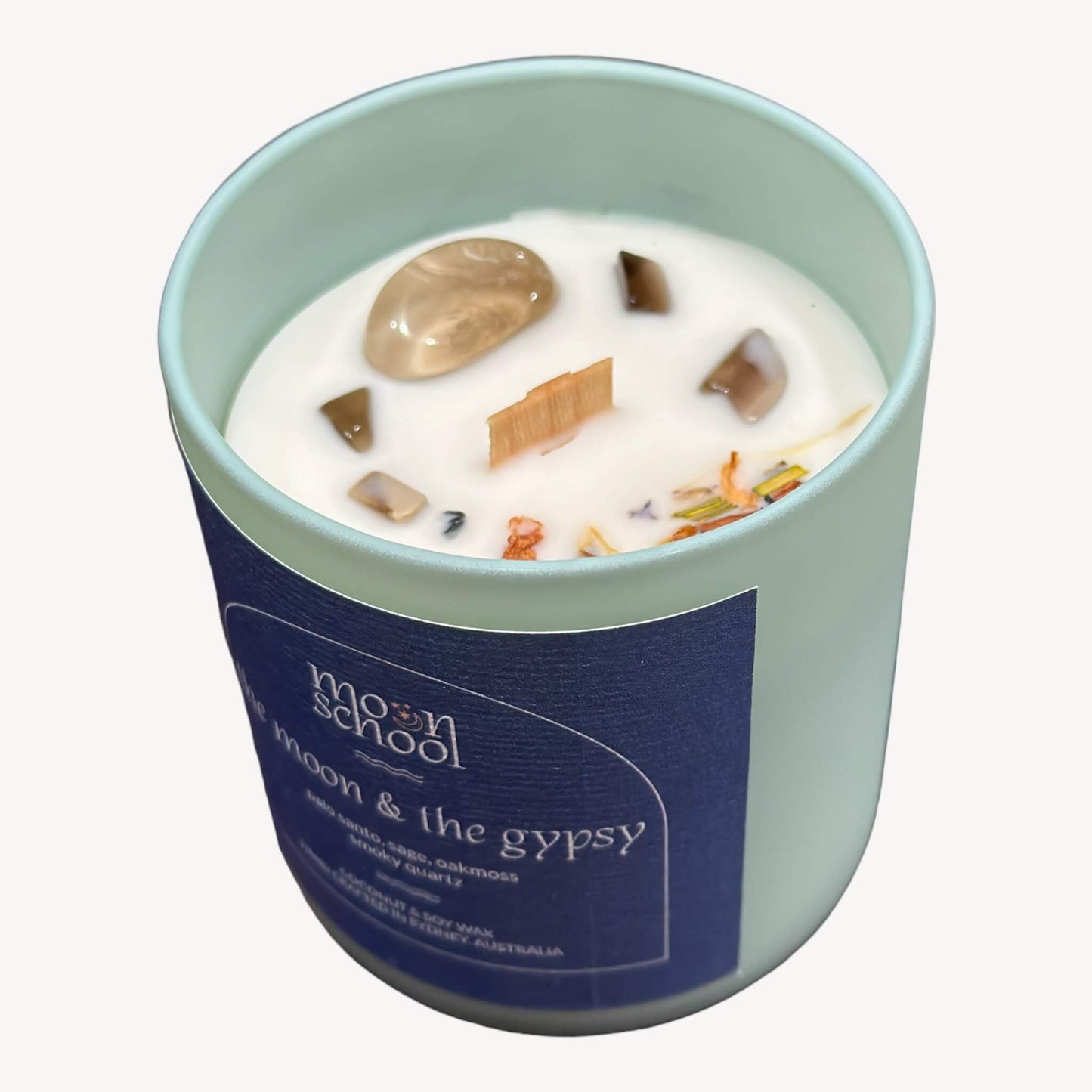 Top view of the crystal decor for The Moon and The Gypsy Crystal candle showing the timber wick, herbs and smoky quartz crystals