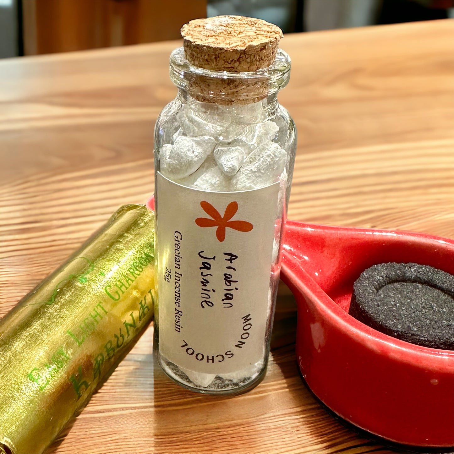 
                  
                    Bottle of Grecian Arabian Jasmine Incense Resin elegantly placed on a bench, accompanied by an incense burner ceramic dish and a roll of Easy-Light Charcoals. Create a fragrant oasis with this A Grade quality resin, ideal for enhancing your space and spiritual practices.
                  
                