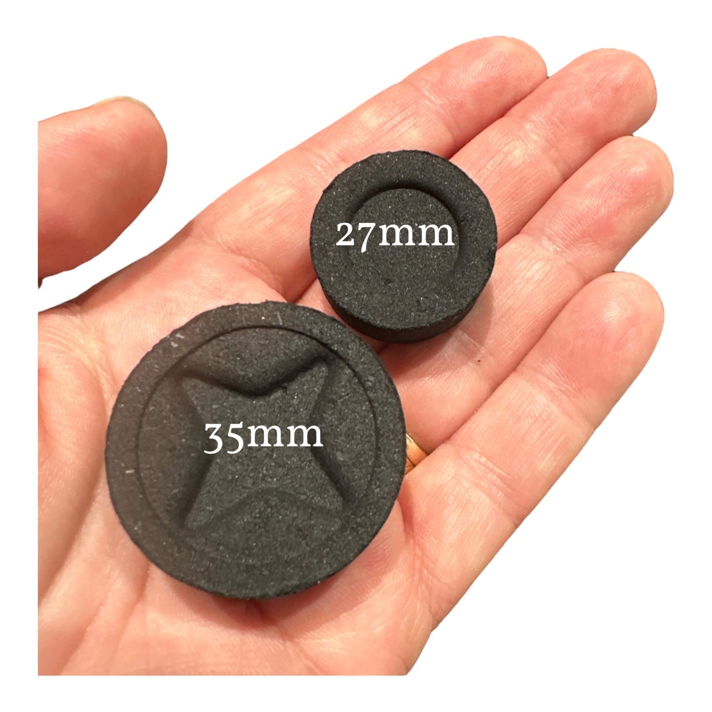 Hand holding individual Easy-Light Charcoal Discs in two sizes (27mm and 35mm). These charcoals are perfect for burning incense resins, providing a quick and efficient way to enhance your space with delightful fragrances.