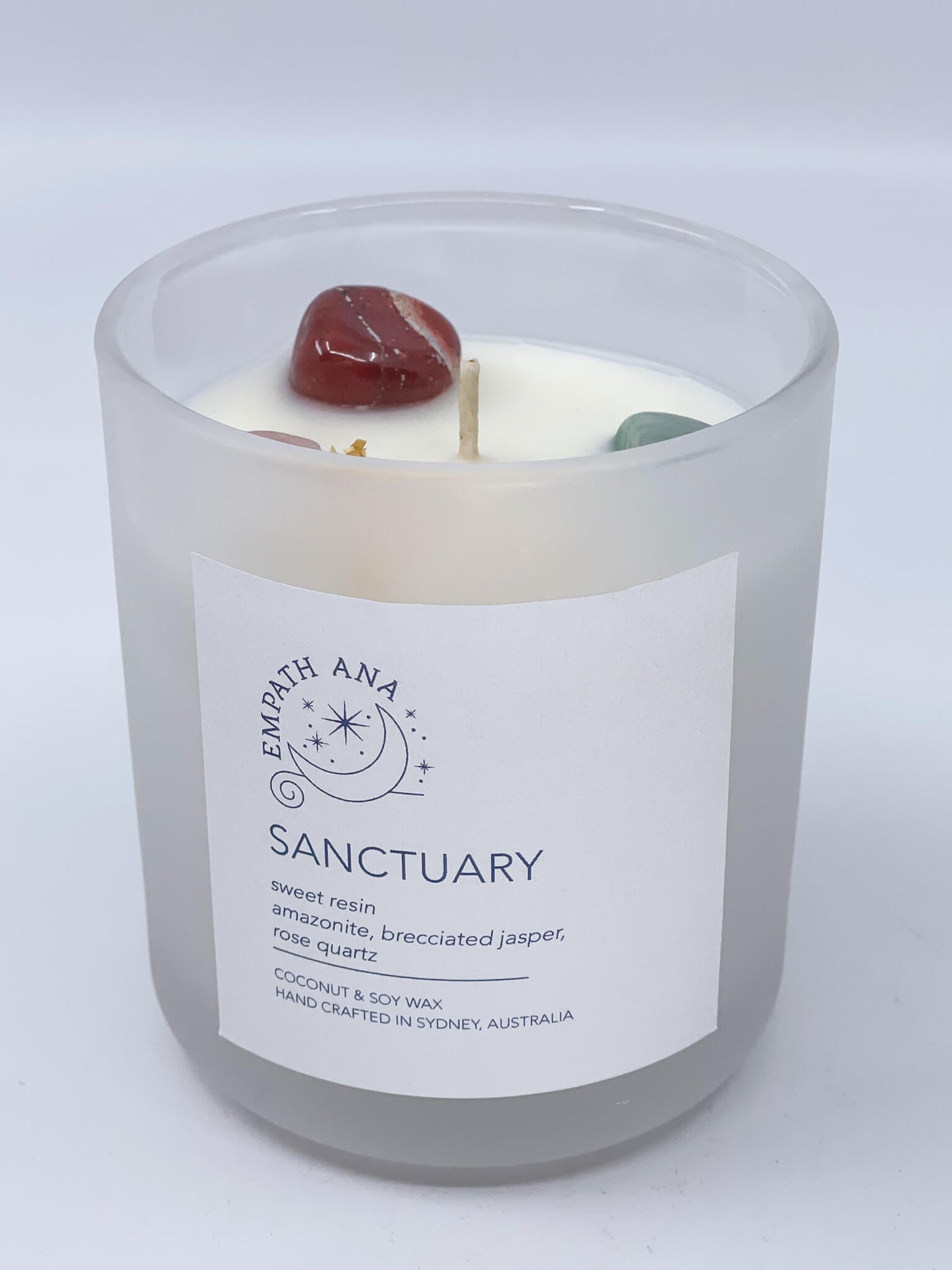 
                  
                    Front of Medium Sanctuary Crystal Candle: A captivating crystal candle by Empath Ana, infused with Amazonite, Brecciated-Jasper, and Rose Quartz, topped with a sweet resin fragrance. Medium size (200mls).
                  
                