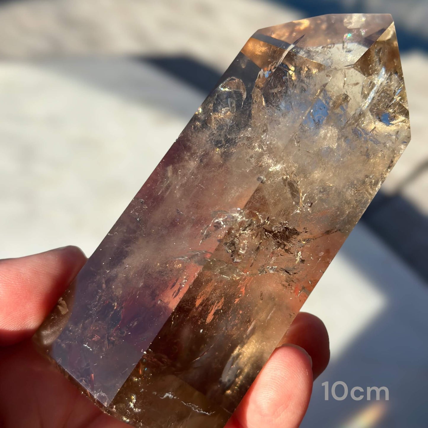 Front of 10cm Smoky Quartz Crystal Generator held in a hand: A stunning 10cm Smoky Quartz crystal generator, displaying its intricate natural patterns and hues.
